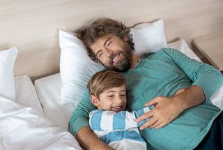 Mann im Hotelzimmer Bett mit Kind im Arm