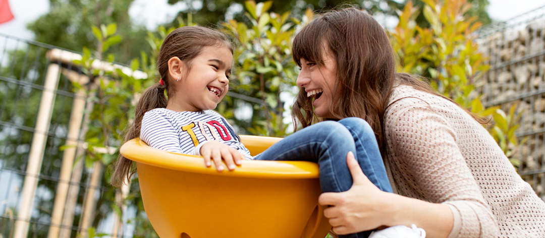 Frau spielt mit Mädchen auf dem Spielplatz